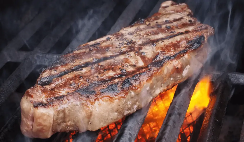 Lamb Sirloin Steak perfectly grilled and garnished with herbs on a white plate.